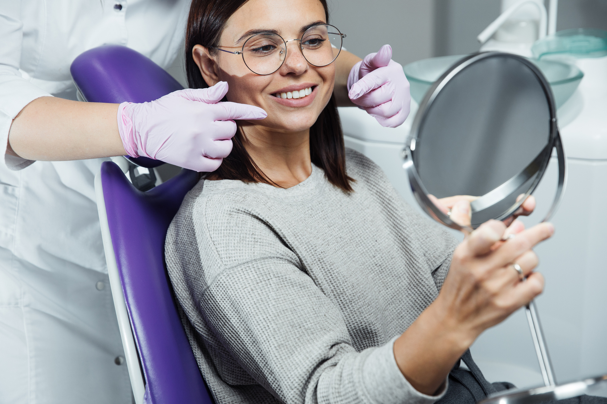 Beautiful woman at the dentist looking at her beautiful teeth. Dentist
